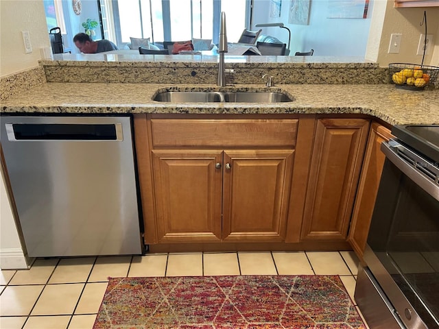 kitchen with appliances with stainless steel finishes, kitchen peninsula, sink, and light tile patterned floors