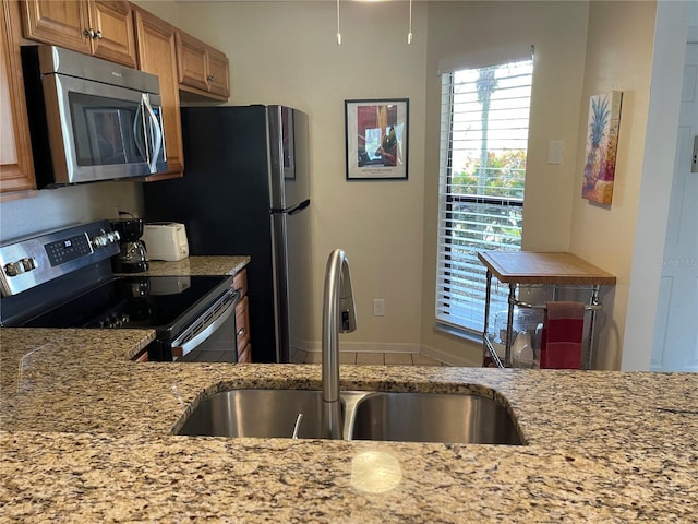 kitchen with light stone countertops, appliances with stainless steel finishes, and sink