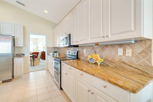 kitchen with vaulted ceiling, appliances with stainless steel finishes, white cabinetry, decorative backsplash, and light stone countertops