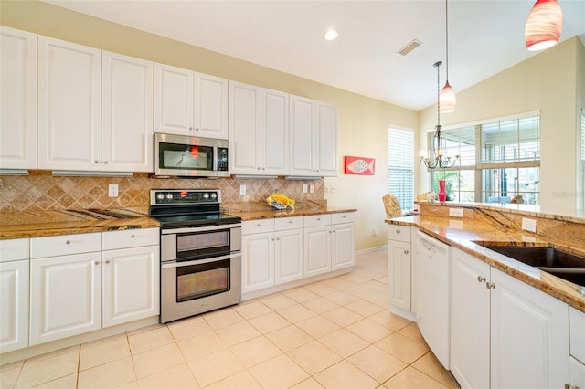 kitchen featuring white cabinetry, vaulted ceiling, pendant lighting, stainless steel appliances, and light stone countertops