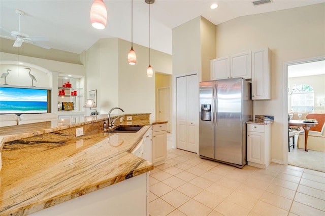 kitchen with decorative light fixtures, white cabinetry, sink, stainless steel fridge, and light stone counters