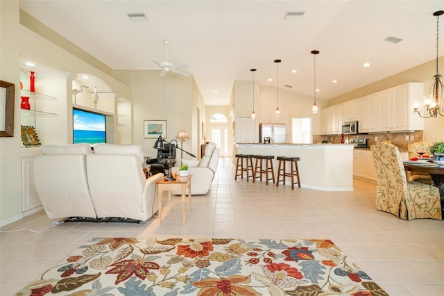 living room featuring ceiling fan with notable chandelier, high vaulted ceiling, and light tile patterned flooring