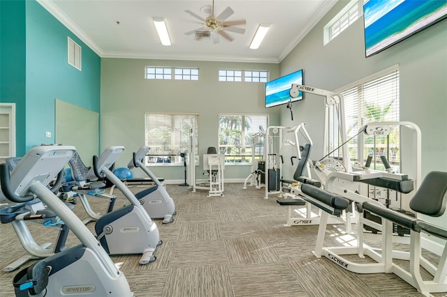 gym featuring light carpet, a towering ceiling, and ornamental molding