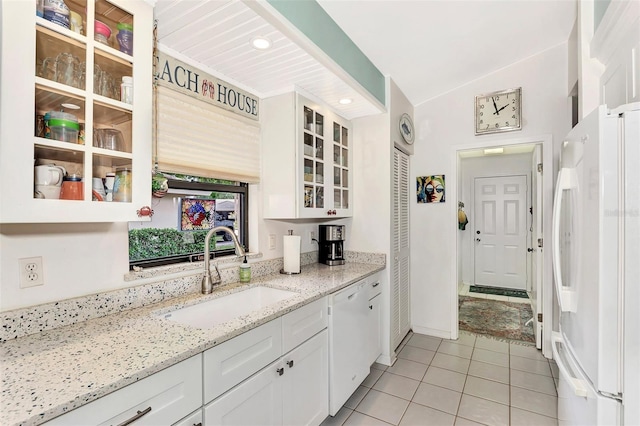 kitchen featuring lofted ceiling, sink, white appliances, light stone countertops, and white cabinets