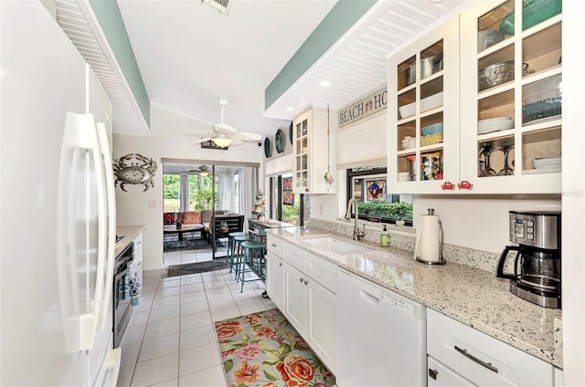 kitchen featuring sink, white cabinets, light tile patterned floors, ceiling fan, and white appliances