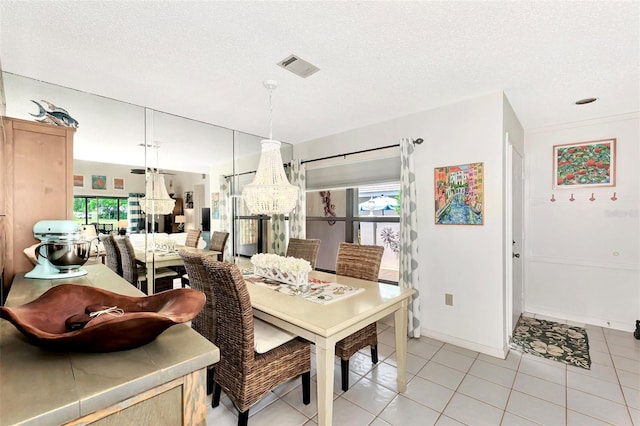 dining room with a healthy amount of sunlight, light tile patterned floors, and a textured ceiling