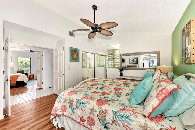 bedroom featuring ceiling fan, lofted ceiling, light hardwood / wood-style flooring, and a textured ceiling