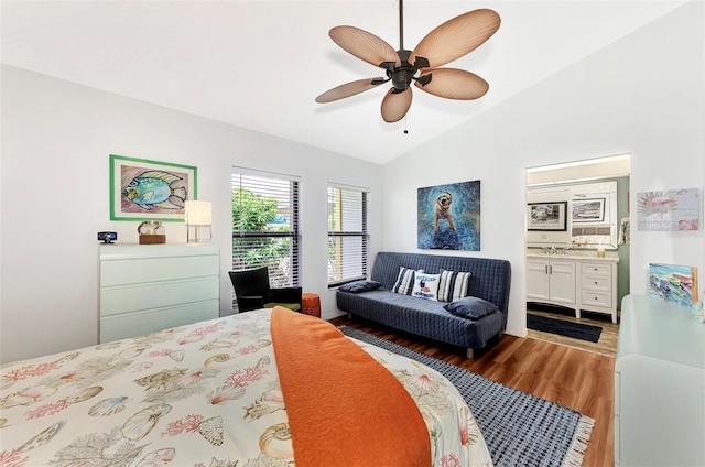 bedroom featuring ceiling fan, connected bathroom, vaulted ceiling, and hardwood / wood-style floors