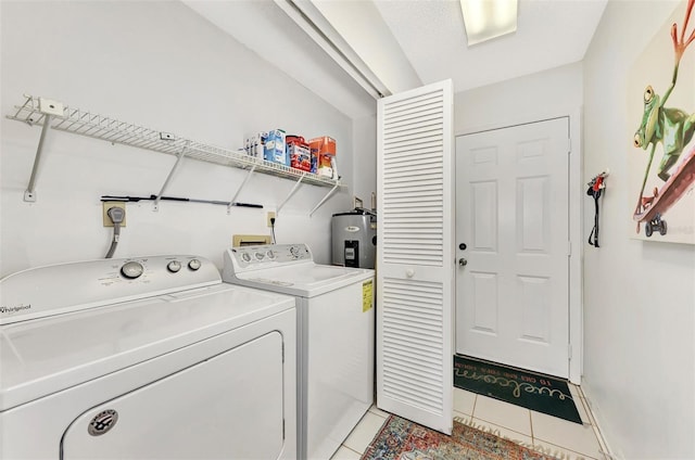 clothes washing area with electric water heater, washer and dryer, and light tile patterned floors