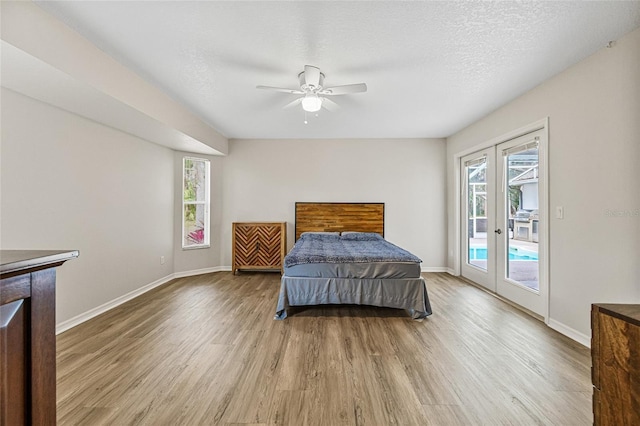 bedroom with french doors, a textured ceiling, light hardwood / wood-style flooring, and access to outside