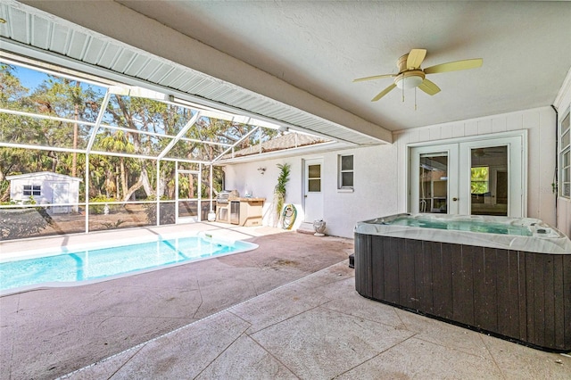 view of pool with area for grilling, ceiling fan, glass enclosure, a hot tub, and a patio area