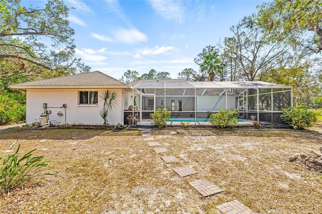 back of property featuring a pool, a yard, and glass enclosure