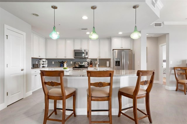 kitchen featuring an island with sink, white cabinets, and appliances with stainless steel finishes