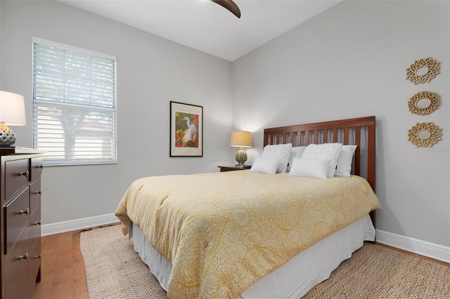 bedroom with ceiling fan, vaulted ceiling, and light wood-type flooring