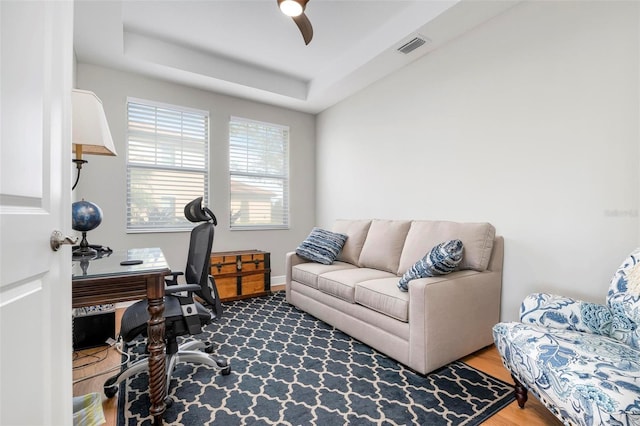 office area with a raised ceiling, hardwood / wood-style flooring, and ceiling fan