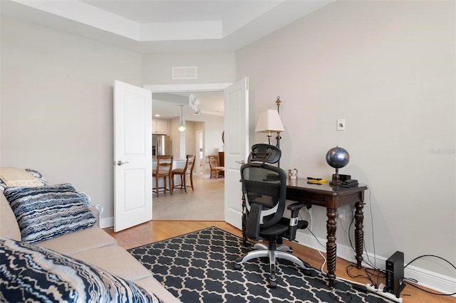 office with hardwood / wood-style floors and a tray ceiling