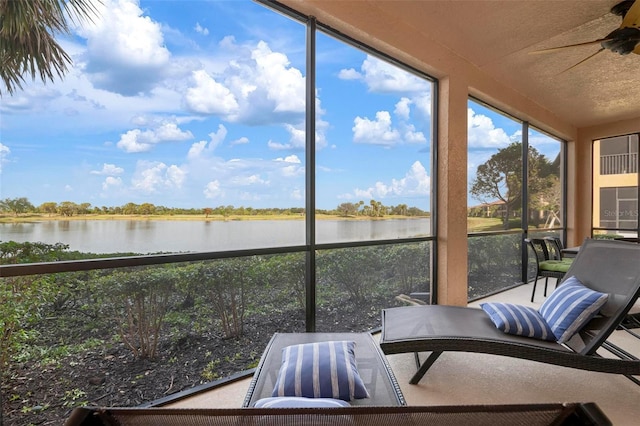 sunroom with a water view and ceiling fan