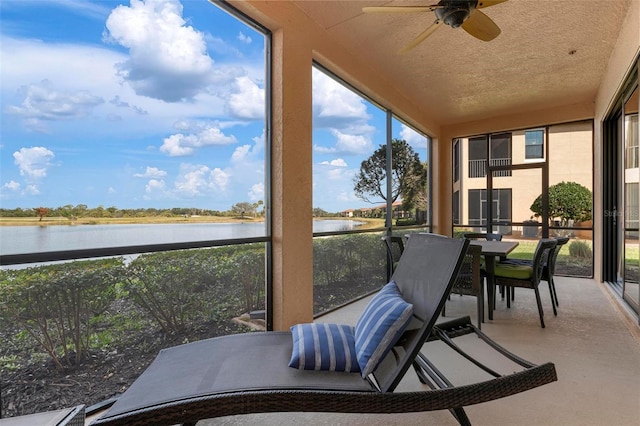 sunroom featuring a water view and ceiling fan