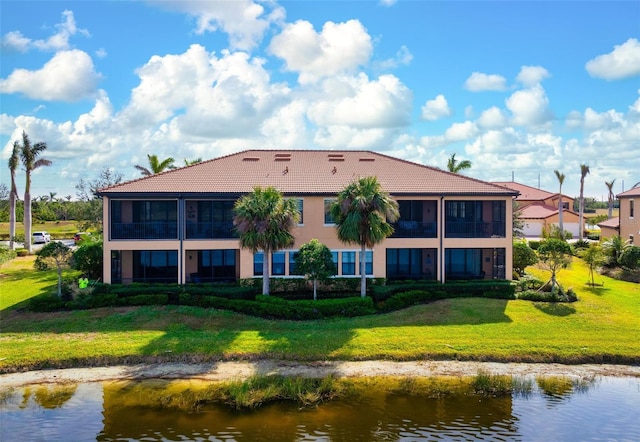 back of house with a yard, a sunroom, and a water view