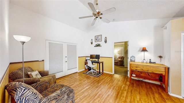 living area with wood-type flooring, lofted ceiling, ceiling fan, a textured ceiling, and french doors