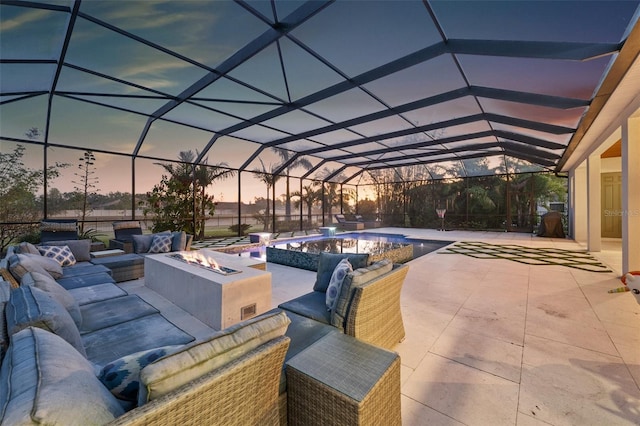 patio terrace at dusk featuring a lanai and an outdoor living space with a fire pit