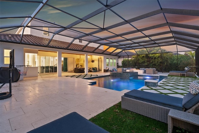 pool at dusk with a lanai, a patio area, a jacuzzi, an outdoor hangout area, and pool water feature