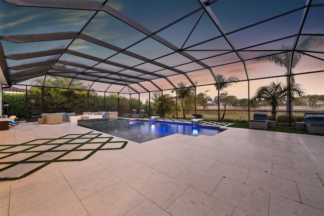 pool at dusk with outdoor lounge area, a patio, glass enclosure, a jacuzzi, and pool water feature