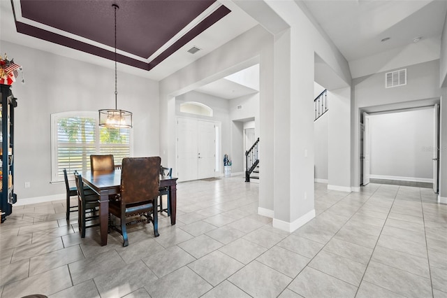 dining room featuring a towering ceiling, light tile patterned floors, a chandelier, and a tray ceiling