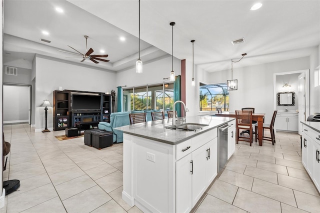 kitchen featuring sink, hanging light fixtures, a center island with sink, dishwasher, and white cabinets