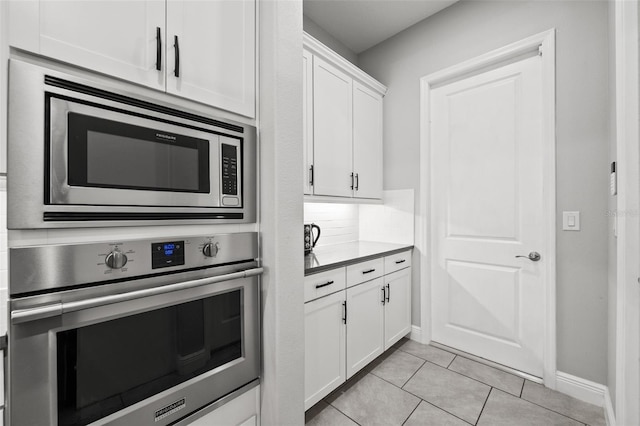 kitchen featuring white cabinetry, stainless steel appliances, tasteful backsplash, and light tile patterned floors