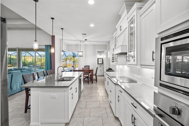 kitchen with stainless steel appliances, sink, an island with sink, and white cabinets