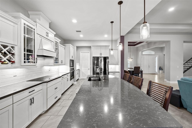 kitchen with white cabinetry, decorative light fixtures, dark stone countertops, stainless steel appliances, and backsplash