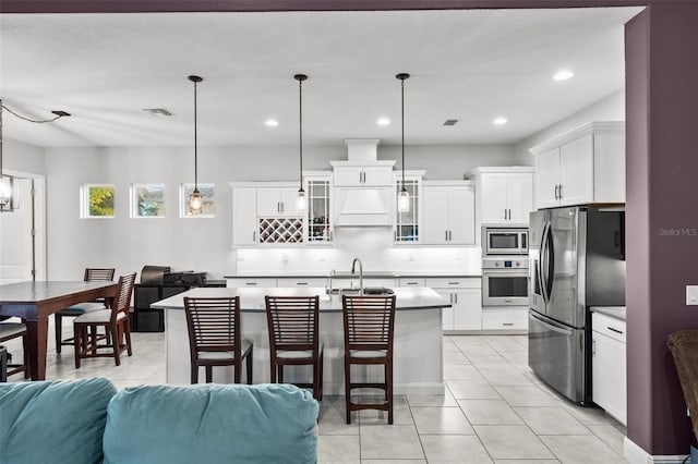 kitchen featuring a breakfast bar, pendant lighting, an island with sink, sink, and stainless steel appliances