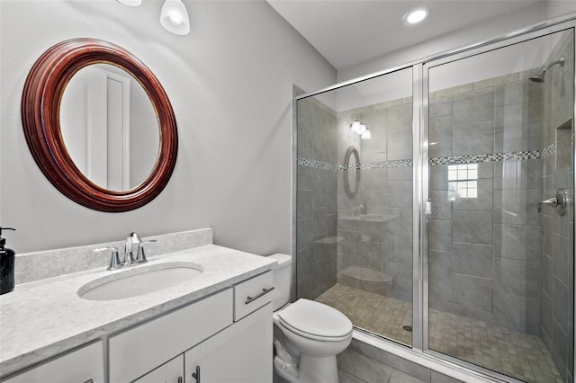 bathroom featuring tile patterned flooring, toilet, vanity, and a shower with shower door