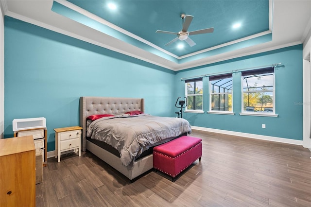 bedroom featuring hardwood / wood-style floors, a tray ceiling, ornamental molding, and ceiling fan