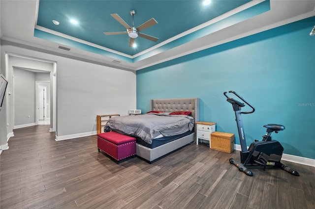 bedroom featuring dark hardwood / wood-style floors, ornamental molding, and a tray ceiling