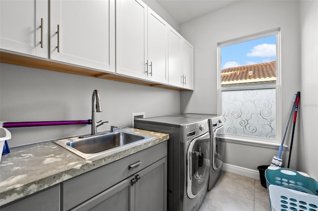 clothes washing area with light tile patterned flooring, cabinets, washer and clothes dryer, and sink