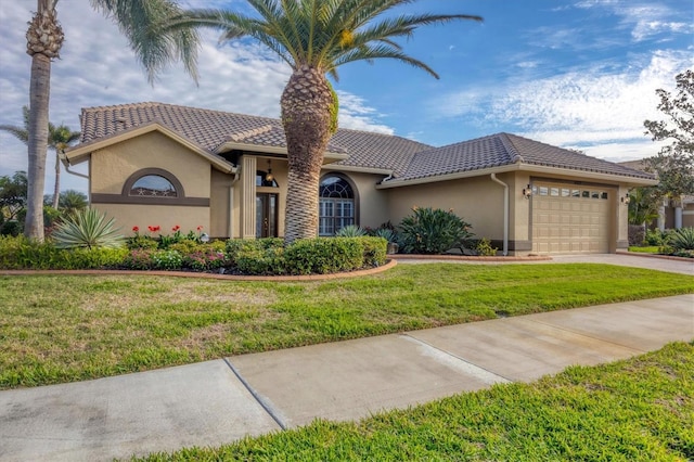 mediterranean / spanish house featuring a garage and a front yard