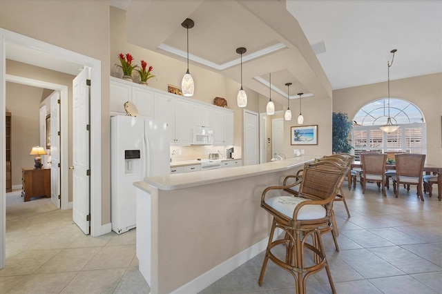 kitchen with decorative light fixtures, light tile patterned floors, a kitchen island, white appliances, and white cabinets