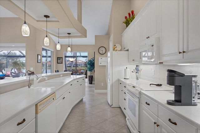 kitchen with sink, white appliances, white cabinetry, backsplash, and decorative light fixtures