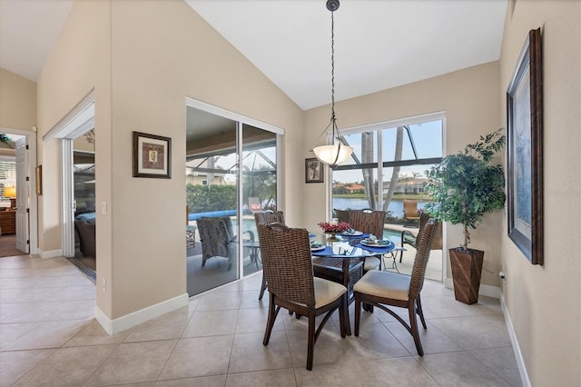 tiled dining area featuring a water view and lofted ceiling