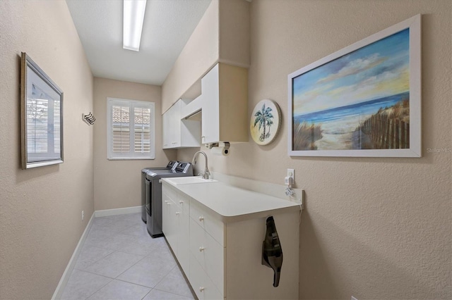 clothes washing area featuring sink, washing machine and dryer, cabinets, and light tile patterned flooring