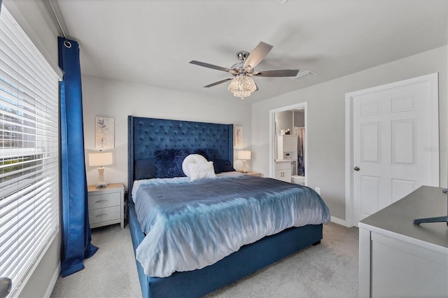 carpeted bedroom with ensuite bathroom and ceiling fan