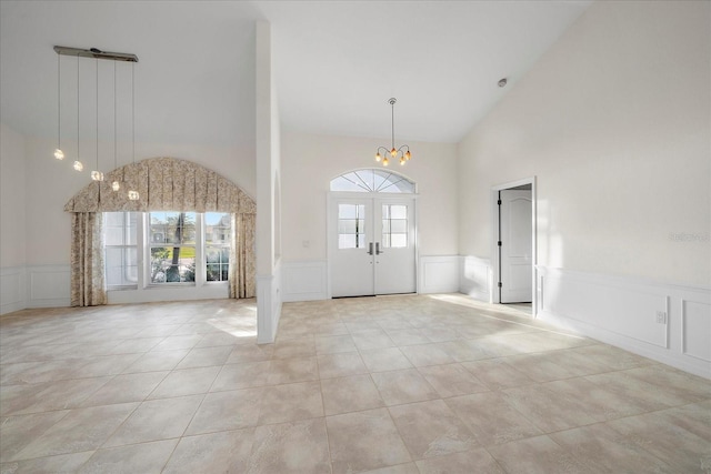 foyer with light tile patterned flooring, high vaulted ceiling, a chandelier, and french doors