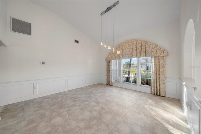 spare room with a wainscoted wall, a decorative wall, visible vents, and high vaulted ceiling