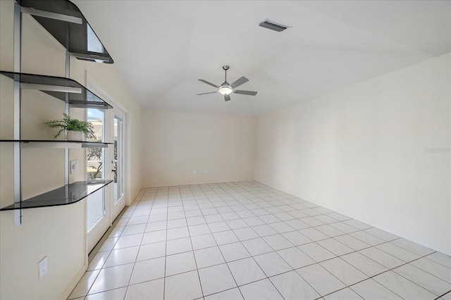 spare room with vaulted ceiling, light tile patterned floors, visible vents, and ceiling fan