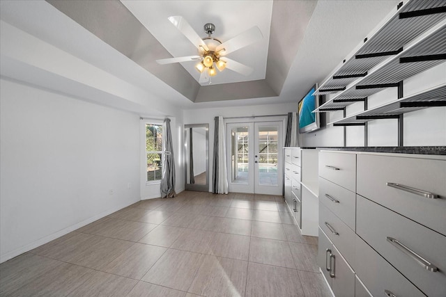 interior space with french doors, ceiling fan, a tray ceiling, and light tile patterned floors