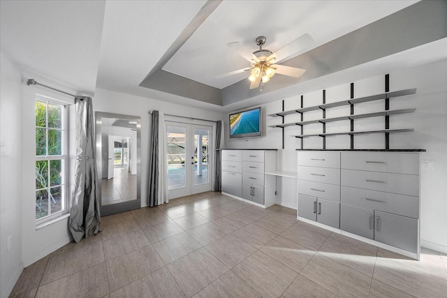 spare room featuring ceiling fan, french doors, a raised ceiling, and baseboards