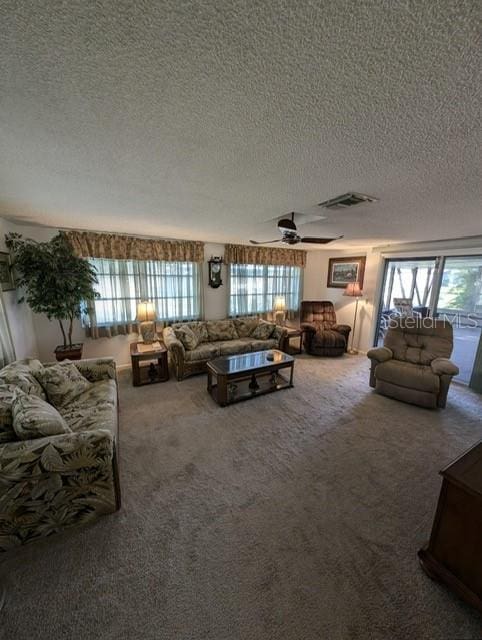 carpeted living room featuring a textured ceiling and ceiling fan