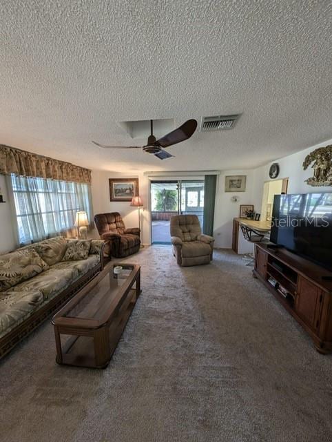 living room featuring ceiling fan, carpet, and a textured ceiling